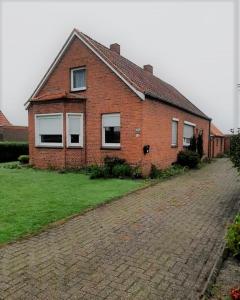 a brick house with windows on a brick road at Monteurzimmer Ausma Wymeer Bunde - FeWo Vakantiehuis Heerenland in Bunde