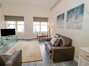 uma sala de estar com um sofá e uma televisão em Gerrard House Apartment em Llandudno