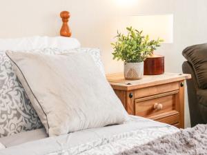 a pillow on a bed with a plant on a nightstand at Gerrard House Apartment in Llandudno
