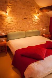 una camera da letto con un letto con lenzuola bianche e coperta rossa di Auberge de la Fontaine a Villiers-sur-Suize