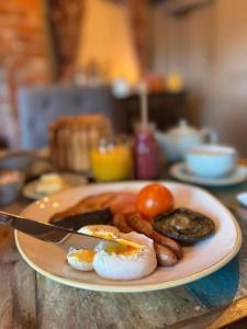 un plato de comida con huevos y salchichas en una mesa en Devonshire Arms Inn en Cracoe