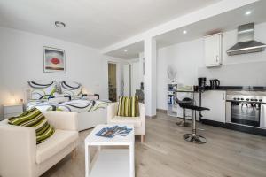 een woonkamer met 2 witte banken en een keuken bij Casita Emma in Playa Blanca