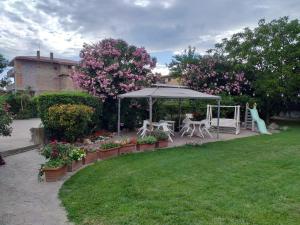 a garden with a gazebo and chairs and flowers at Residence Speedy in Fiumicino