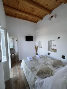 - une chambre blanche avec un lit et une télévision à écran plat dans l'établissement Siesta Villas nearby Tzanaki Beach Livadi, à Livadi Astypalaias