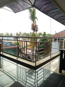a balcony with a view of a palm tree and water at Hotel Abad Baru 1 in Pangandaran