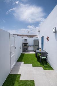 een kleine achtertuin met een tafel en groen gras bij Casita Emma in Playa Blanca