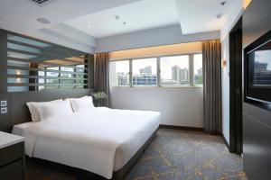 una camera da letto con un grande letto bianco e finestre di The Cityview - Chinese YMCA of Hong Kong a Hong Kong