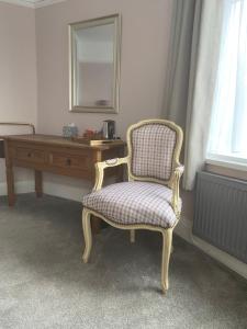 a chair sitting in front of a desk with a mirror at Devonshire Arms Inn in Cracoe