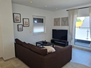 sala de estar con sofá marrón y TV en Penthaus, en Soltau
