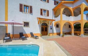 a building with a pool and chairs and an umbrella at Holiday House Karla Valentina in Škropeti