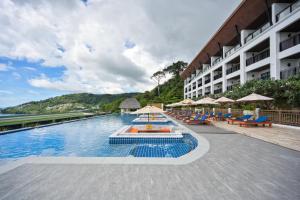 une piscine dans un hôtel avec des chaises et des parasols dans l'établissement Andamantra Resort and Villa Phuket - SHA Extra Plus, à Patong Beach