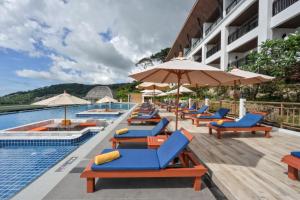 巴東海灘的住宿－Andamantra Resort and Villa Phuket - SHA Extra Plus，游泳池旁的一排躺椅和遮阳伞