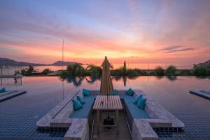una piscina con ombrellone e tavolo con cuscini blu di Andamantra Resort and Villa Phuket - SHA Extra Plus a Patong Beach