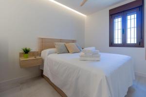 een witte slaapkamer met een bed met handdoeken erop bij Madera Negra in Córdoba
