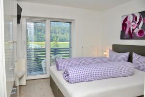 a bedroom with a bed with purple sheets and a window at Pension Ferienwohnung Pirhofer in Kramsach