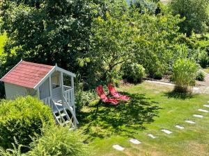 Schorndorf的住宿－Holiday Home Ederer by Interhome，花园内有两把红色椅子,设有一个小棚子