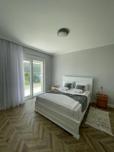 a white bedroom with a bed and a large window at Villa Le Grand Bleu in Đenovići