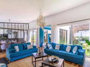 een woonkamer met blauwe banken en een eetkamer bij Holiday Home Indigo-Vue Mer et Piscine chauffée by Interhome in Saint-Brevin-les-Pins