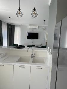 a white kitchen with a sink and a tv at Villa Le Grand Bleu in Ðenovići
