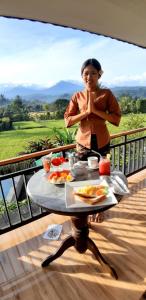 The Aroma Villa Munduk في Mayong: امرأة تقف أمام طاولة مع الطعام
