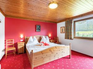 a bedroom with a bed with a red wall at Holiday Home Haus am Sonnenhang by Interhome in Spielbichl