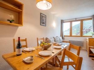 a dining room table with a bottle of wine on it at Apartment Arcelle-4 by Interhome in Val Thorens