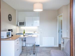 a kitchen with white cabinets and a table and chairs at Apartment Fleur Marine-5 by Interhome in Cabourg