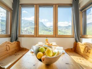 a table with a bowl of fruit in a room with windows at Apartment Arcelle-11 by Interhome in Val Thorens