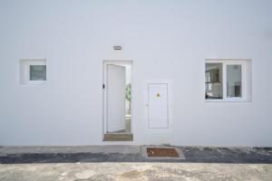 a white building with two windows and a door at Las Rosas in Punta de Mujeres