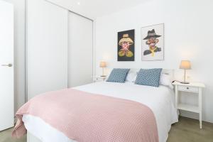 a white bedroom with a white bed with a pink blanket at Las Rosas in Punta de Mujeres