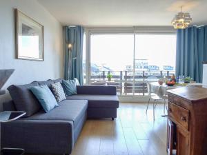 a living room with a blue couch and a large window at Apartment Les Marinas by Interhome in Deauville