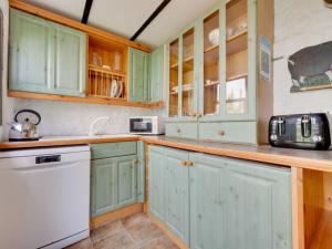 BrynammanにあるHoliday Home Cwmllynfell by Interhomeのキッチン(緑のキャビネット、白い電化製品付)