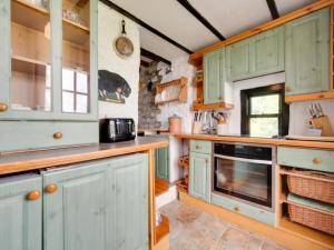 BrynammanにあるHoliday Home Cwmllynfell by Interhomeのキッチン(緑のキャビネット、オーブン付)