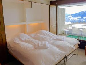 Cama blanca en habitación con ventana grande en Studio Jeanne d'Arc-11 by Interhome en Crans-Montana