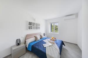 una camera bianca con un letto blu e una finestra di San Carlo Borromeo Apartments by Wonderful Italy a Soiano del Lago