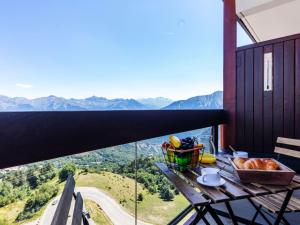 un tavolo con un cesto di cibo su un balcone con montagne di Studio Pegase Phenix-59 by Interhome a Le Corbier