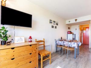 a dining room with a table and a tv on the wall at Studio Pegase Phenix-59 by Interhome in Le Corbier