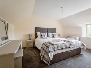 a bedroom with a large bed and a television at Holiday Home Burn Side by Interhome in Brackla