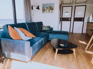 un soggiorno con divano blu e tavolo di Holiday Home De Meerparel by Interhome a Uitgeest