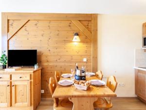 een eetkamer met een houten tafel en een televisie bij Apartment Les Alpages du Corbier-7 by Interhome in Le Corbier