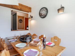 ein Esszimmer mit einem Holztisch und einer Uhr an der Wand in der Unterkunft Apartment Les Alpages du Corbier-10 by Interhome in Le Corbier