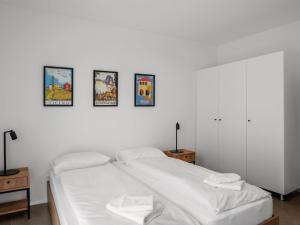 uma cama branca num quarto com quatro fotografias na parede em Apartment LocTowers A3-6-3 by Interhome em Locarno