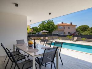 jadalnia ze stołem i krzesłami przy basenie w obiekcie Holiday Home Villa Palma by Interhome w mieście Pinezići