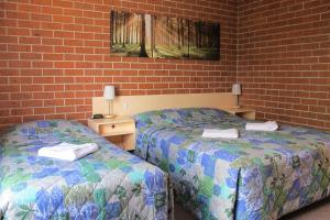 two beds sitting next to a brick wall at Greenslopes Motor Inn in Brisbane