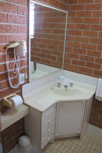 Greenslopes Motor Inn في بريزبين: حمام مع حوض وجدار من الطوب