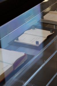 a glass shelf with a book and papers on it at Art Hotel Olympic in Turin