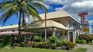 a hotel with a palm tree in front of a building at Welcome Home Motel Rockhampton in Rockhampton