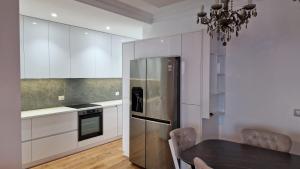 a kitchen with a table and a stainless steel refrigerator at Pirro Luxury Apartment in Sarandë