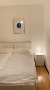 1 dormitorio con cama blanca y mesita de noche con lámpara en Hotel Fonte dei Fiori, en Caslano