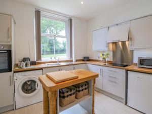 a kitchen with white cabinets and a washer and dryer at Church View Cottage in Bishop Auckland